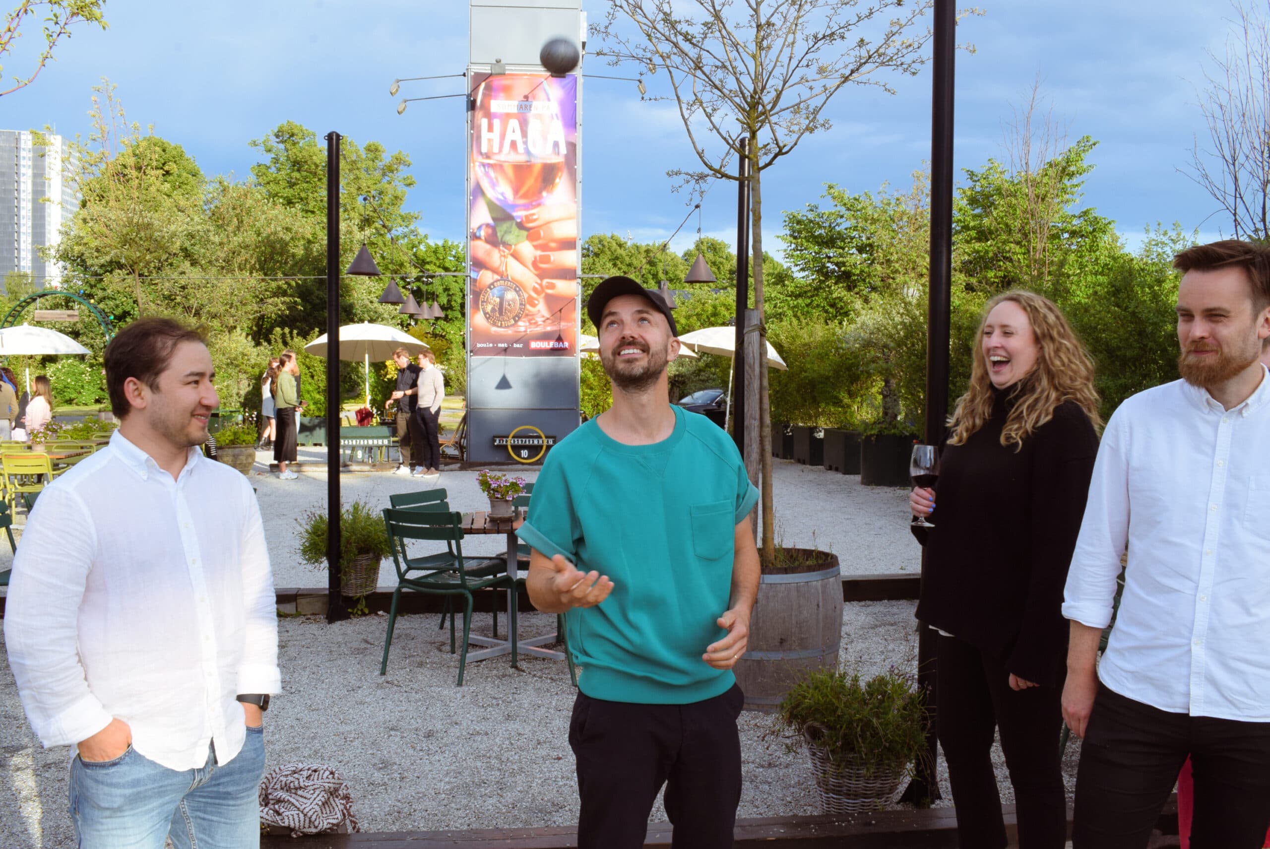 A group of Swace colleagues enjoying an after-work game of boule outdoors, with one colleague tossing a boule ball in the air.