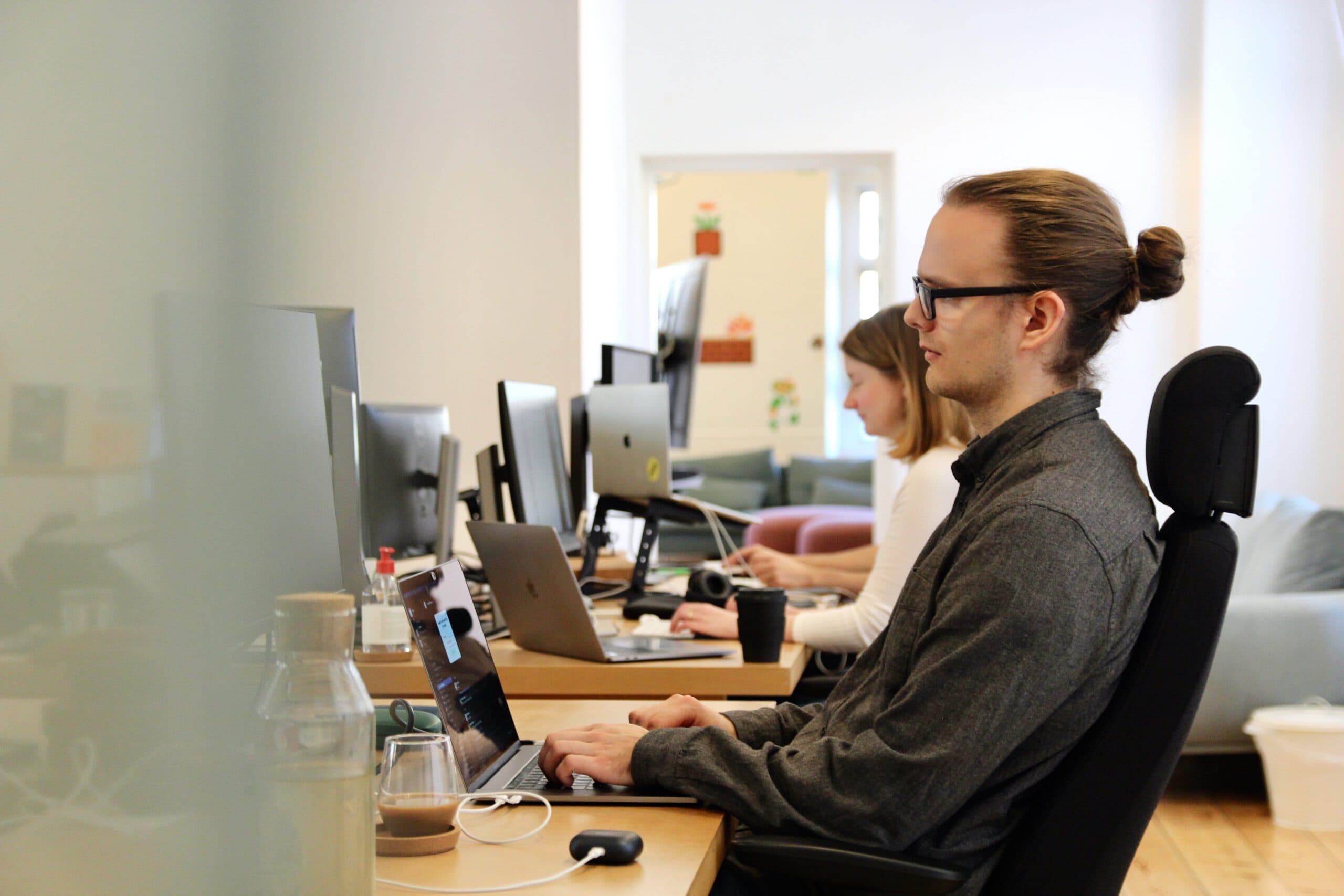 Colleagues working at their desks in the Swace office, focusing on their laptops during a project.