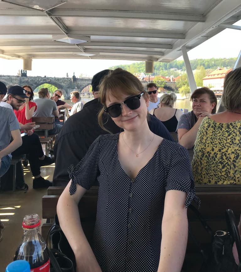 Amanda Alm, developer at Swace, photographed during a company conference boat tour, with a historic bridge and other participants in the background.