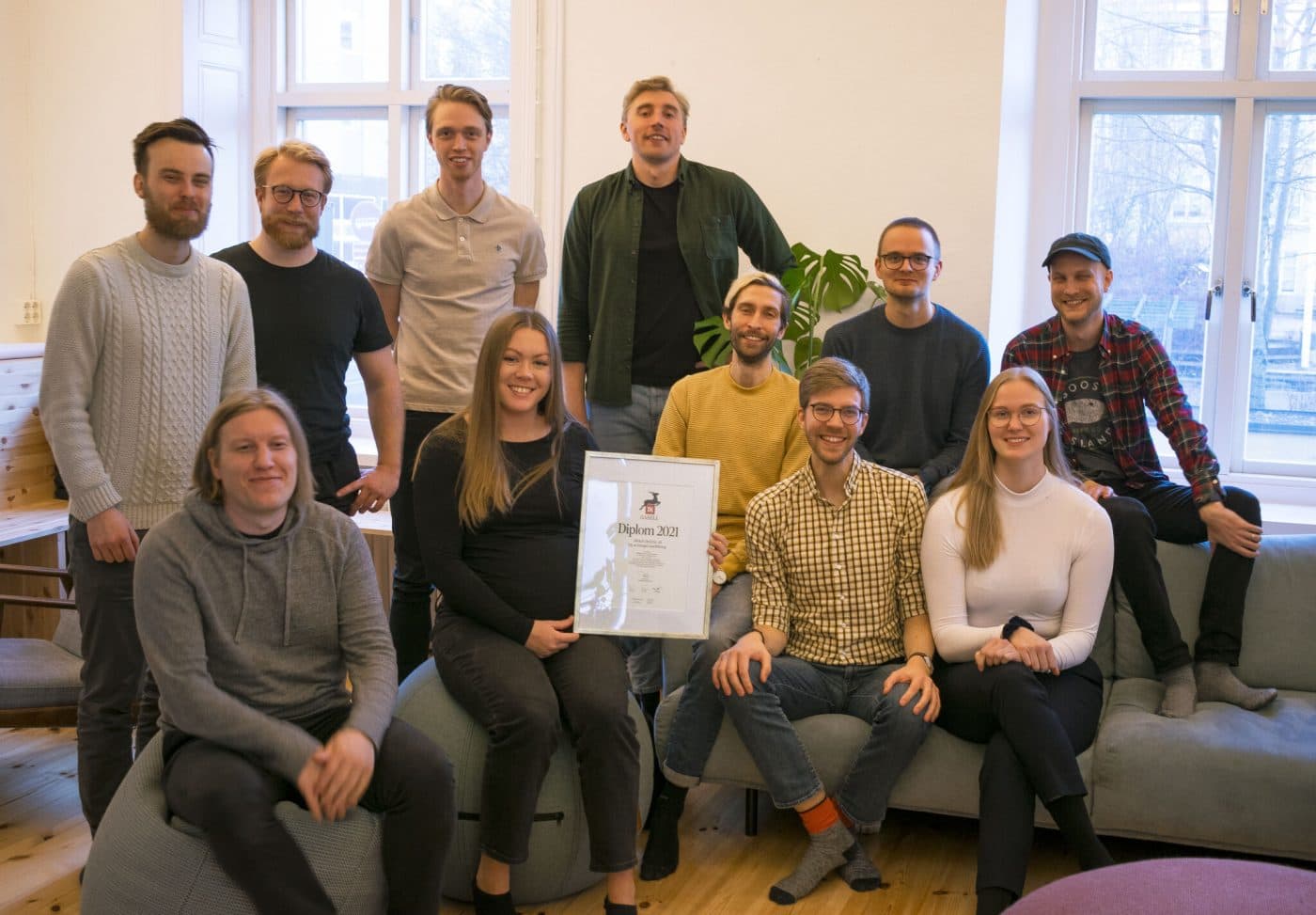 Team group photo indoors, with one person holding a framed diploma labeled 'Diplom 2021'