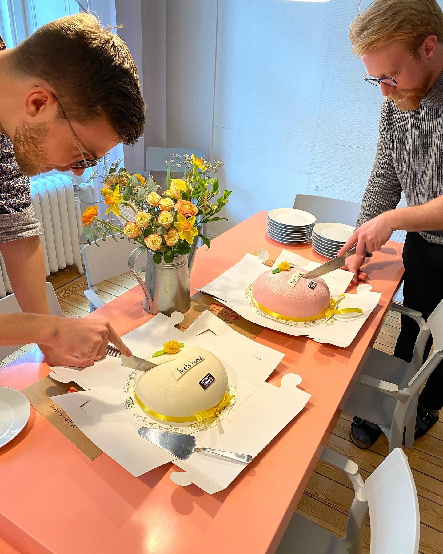 Two Swace colleagues cutting celebratory cakes at the office after winning “Årets Komet” award.