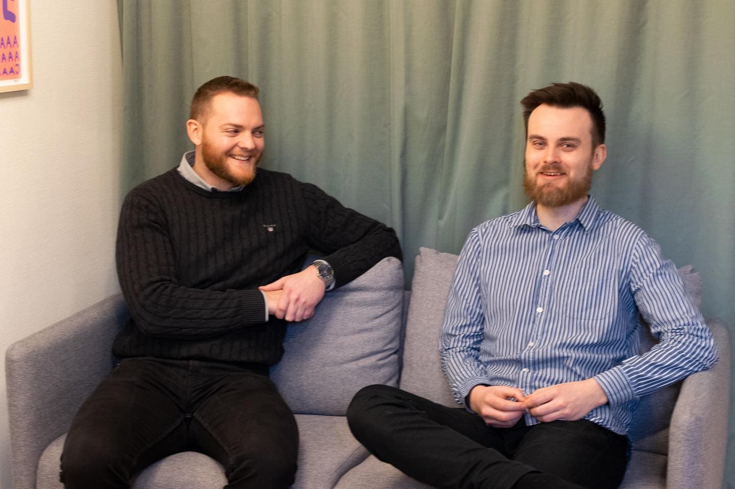 Two colleagues sitting on a sofa, talking during a meeting.