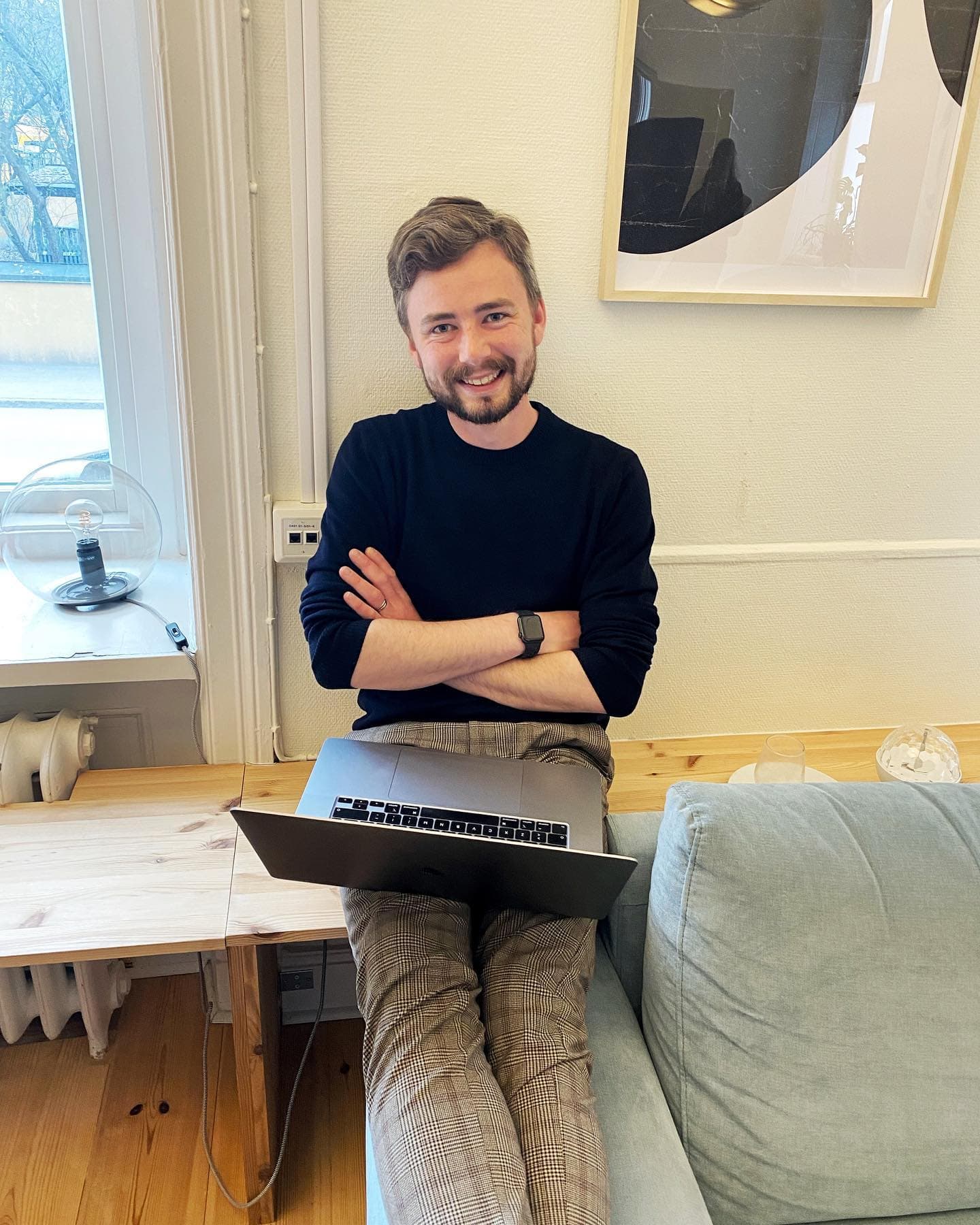 A colleague sitting on a bench with a laptop, smiling at the camera.