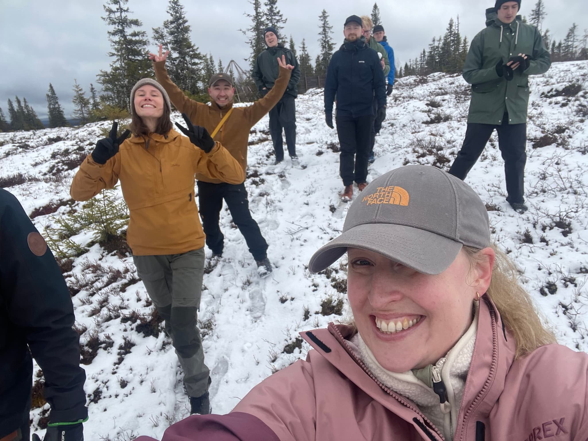 A group of colleagues hiking in snowy mountains near Åre, smiling and enjoying the outdoor team activity.
