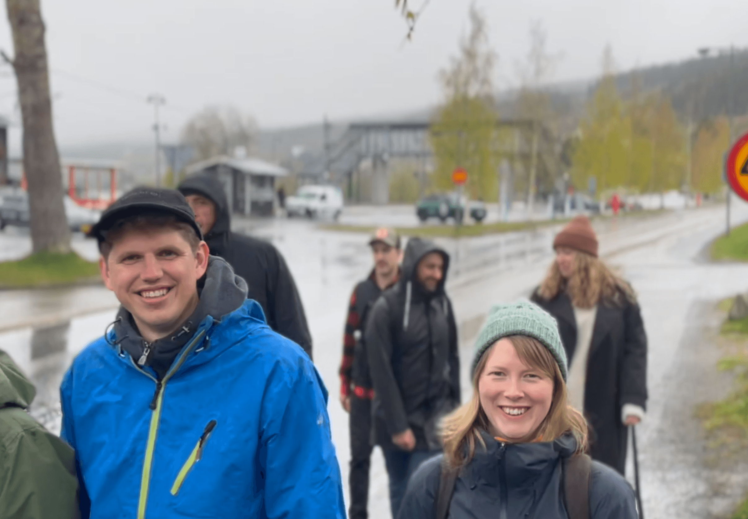 A group of colleagues walking outdoors in Åre on a rainy day, smiling despite the weather during the company conference.