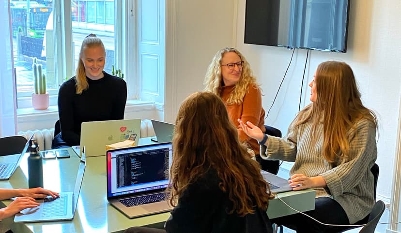 Swace colleagues sitting around a meeting table with laptops, talking and collaborating during a team discussion.